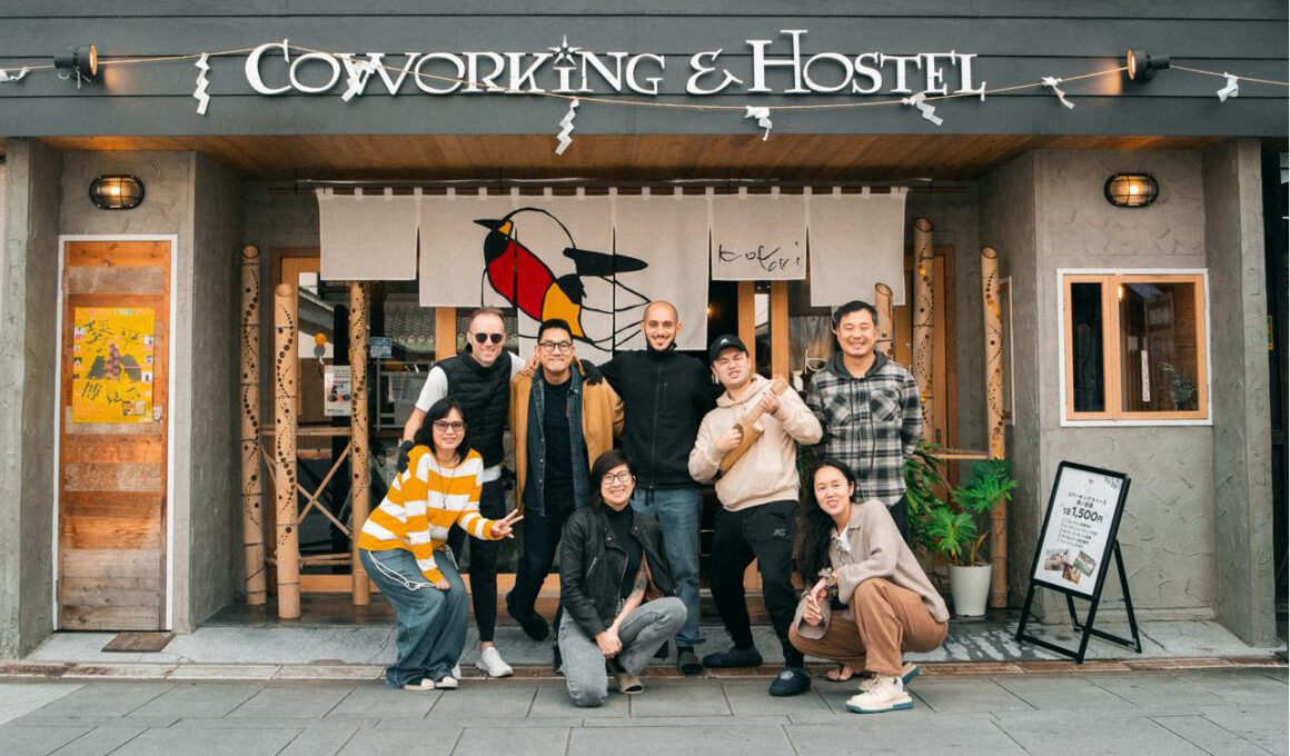 A group of people posing in front of the entrance to a hostel in Japan