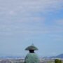 A statue of a monk overlooking an urban landscape under a blue sky: Shikoku Henro trail