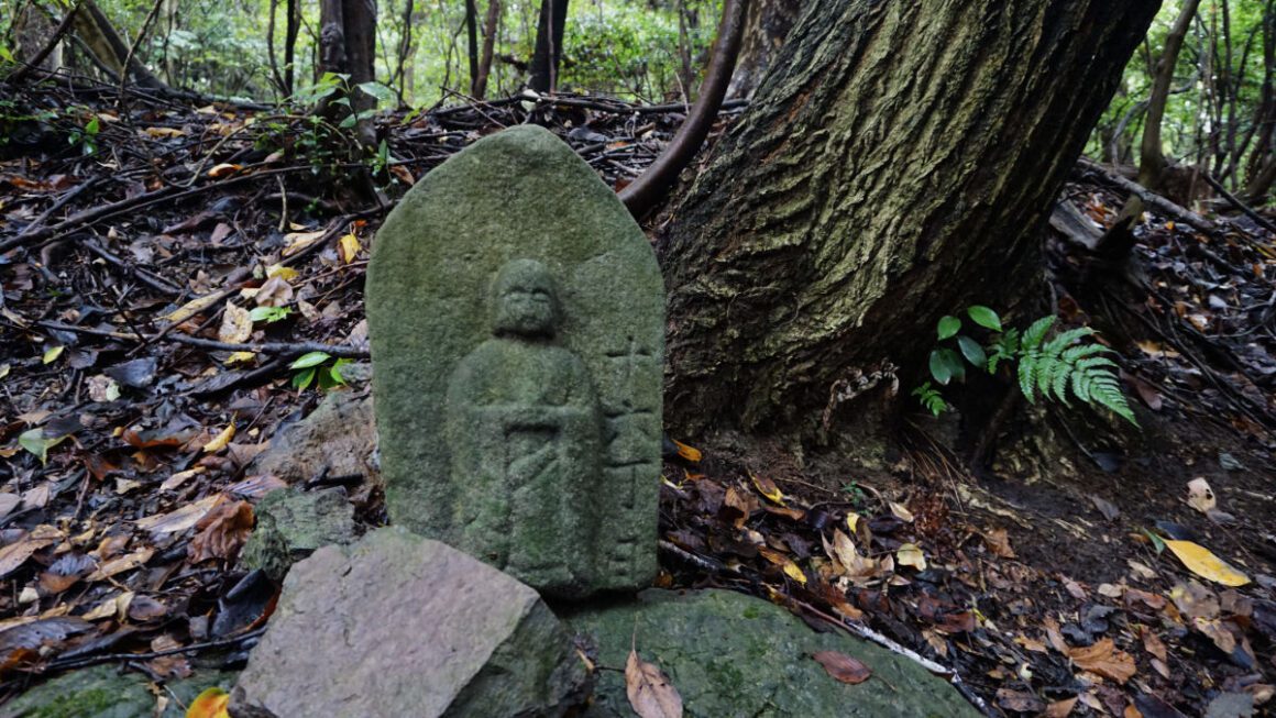 A small stone shrine among fallen leaves on the Shikoku Henro trail